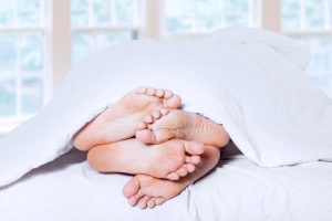 Close-up of couple's feet cuddling. shost at bedroom